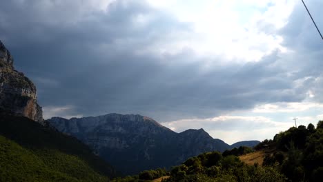 Sun-rays-beaming-through-mountains-onto-the-Tymfi-mountain-range,-wide-shot,-time-lapse