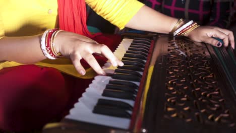 Unrecognizable-married-Indian-woman-playing-music-with-harmonium,-close-up-shot-of-hands,-slow-dolly-shot