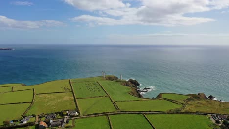 Aerial-shot-of-farmland-with-a-view-of-the-Metal-Man-and-rocky-coastline-of-Waterford-in-the-South-of-Ireland