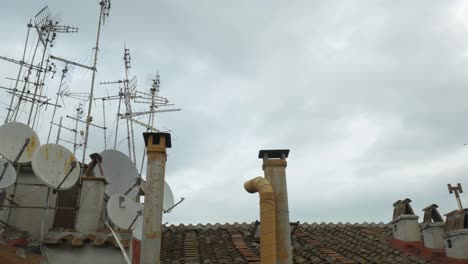 Das-Ziegeldach-Des-Hauses-Und-Eine-Große-Anzahl-Von-Fernsehantennen-Und-Satelliten-Darauf,-Vor-Einem-Bewölkten-Himmel
