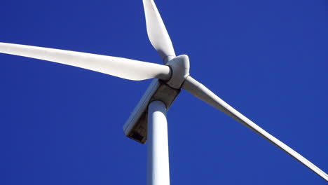 Close-up-view-of-a-wind-turbine's-blades-spinning-against-a-blue-sky-background