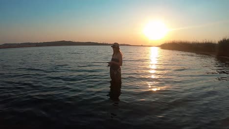 View-of-beautiful-girl-bass-fishing-in-a-lake-with-a-beautiful-sunset-in-the-background-in-South-Africa