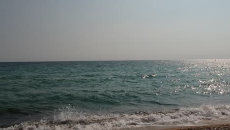 Steady-shot-of-waves-crushing-on-the-sandy-beach-of-a-greek-island