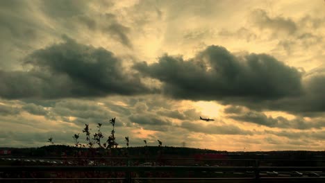 Airplane-against-the-background-of-the-sky-at-sunset,-flying-low-above-the-highway,-lots-of-clouds-in-the-sky
