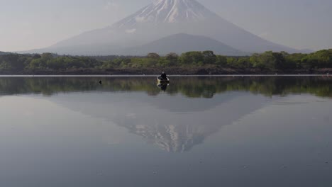 Ríos-Tranquilos-Del-Monte-Fuji-Con-Pescador-En-Bote-Pescando,-Inclinado-Hacia-Arriba-Tiro-Ancho-Extremo