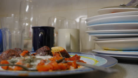 Stack-of-dirty-dishes-and-mouldy-food-in-student-home,-close-up-panning-shot