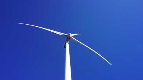 Low-angle-view-of-a-wind-turbine-spinning-on-a-sunny,-clear-autumn-day