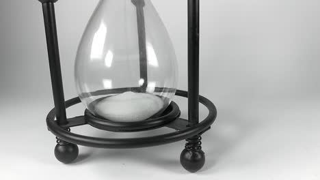 The-bottom-part-of-an-hourglass-with-black-metallic-base-filling-up-with-white-sands-of-time,-ISOLATED,-STILL,-TIMELAPSE
