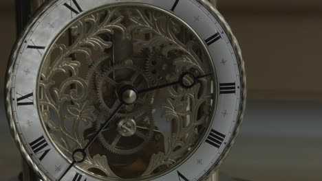 Wider-shot-of-ornate-brass-clock-with-hands-stationary-near-three-o'clock
