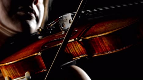 An-extreme-close-up-of-a-female-musician-playing-the-violin,-on-a-seamless-black-studio-background