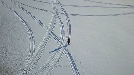 Rotating-aerial-shot-of-man-operating-a-drone-in-snowy-winter-landscape