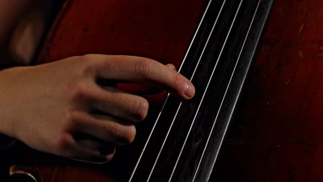 An-extreme-close-up-of-a-person-picking-the-strings-of-a-cello-double-bass