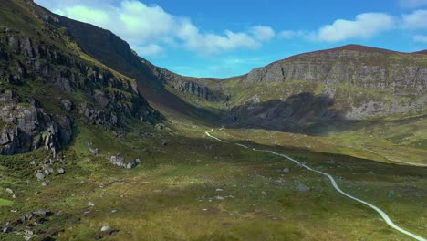 Luftaufnahme-Eines-Bergtals-Und-Eines-Gewundenen-Pfades,-Der-Im-Sommer-Zu-Einem-Wasserfall-Im-Süden-Irlands-Führt