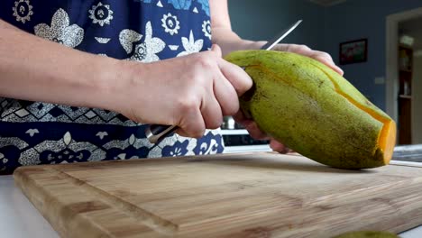 Close-up-peeling-ripe-mango-fruit-with-paring-knife,-food-preparation