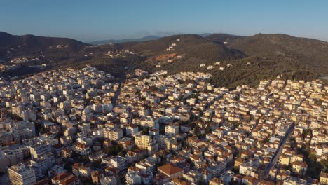Aerial-drone-Flight-descending-to-downtown-mitilini,-houses-on-hills-and-mountains,-mytilene-lesvos,-greece