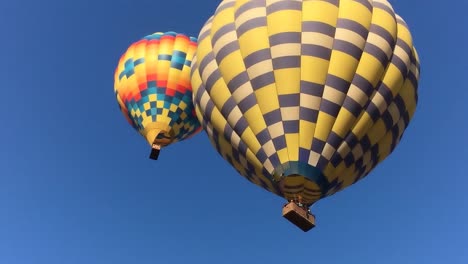 MS-on-hot-air-balloons-as-they-descend,-flame-from-the-boiler-shot-up-from-basket,-blue-sky-in-background