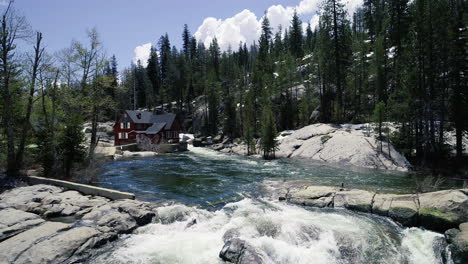 Dolly-forward-revealing-river,-waterfall-and-red-house-by-river