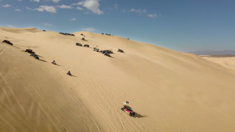 Aerial-of-Buggies-and-ATVs-driving-down-Algodones-sand-dunes,-California