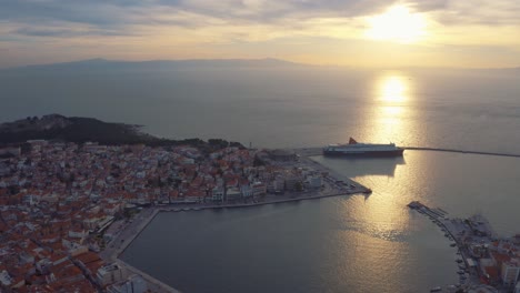 Harbor-of-mitilini-aerial-drone-flight-revealing-sunrise-at-sea-with-ferry-to-athens,-lesvos,-greece