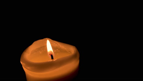 Single-lit-candle-on-black-background-in-slow-motion