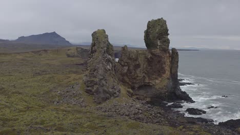 Flying-around-Londrangar,-a-pair-of-rock-pillars-on-the-coast-of-Snaefellsnes-in-Iceland