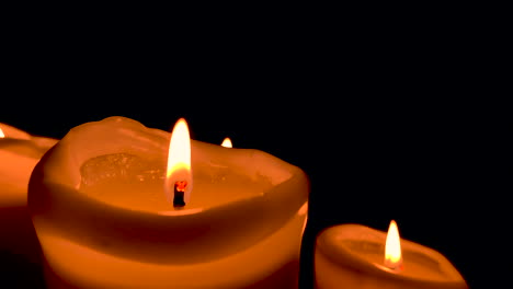 Orange-lit-candle-on-black-background,-small-fire-on-wick:-slow-motion