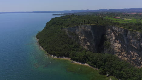 Aerial-shot-backing-away-from-the-cliffs-of-Manerba-at-Lago-Di-Garda-on-a-bright-sunny-day