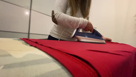 The-woman-irons-a-red-blouse-on-an-ironing-board