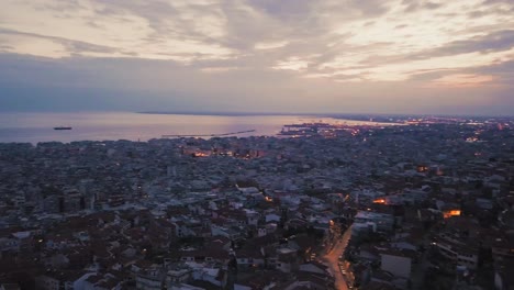 Aerial-footage-of-coastal-city-of-Thessaloniki-by-dusk,-drone-panning