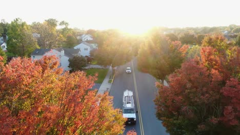 Red,-orange,-yellow-locust-and-maple-trees-in-fall,-autumn-foliage,-cars-whiz-by-in-small-town-America