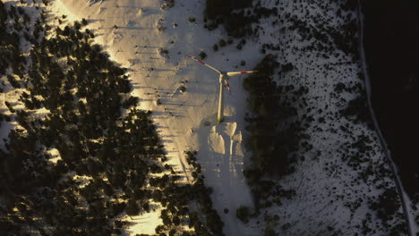 Birdseye-Luftaufnahme-Eines-Schneebedeckten-Plateaus-Mit-Einer-Windkraftanlage
