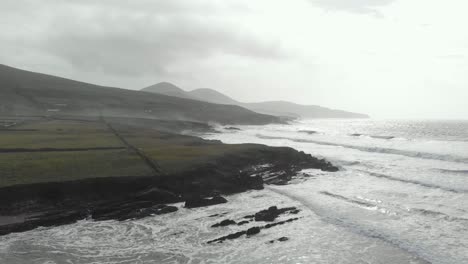 Aerial-of-rising-drone-above-rugged-irish-coastline-with-waves-and-white-spray