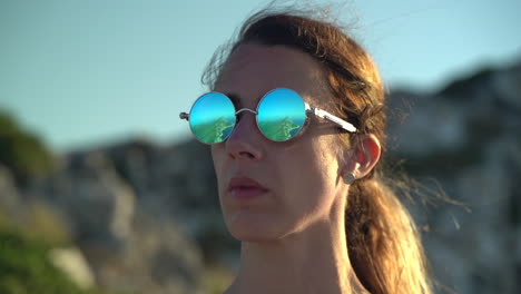 Reflection-of-island-peninsula-off-woman's-polarized-sunglasses