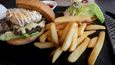 A-delicious-burger-and-fries-served-on-a-beautiful-black-slate-plate