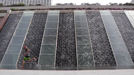 A-man-runs-across-a-beautiful-water-feature-in-Singapore's-business-district