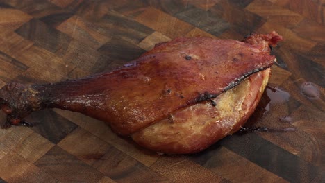 Roasted-Confit-Duck-Leg,-turning-view-in-on-wooden-cutting-board