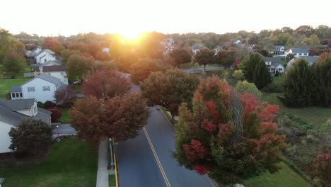 Langsame-Luftdrehungen-Zeigen-Herbstfarben-Während-Des-Klaren-Herbstsonnenuntergangs,-Heuschrecken--Und-Ahornbäume-Säumen-Straßen-Und-Häuser