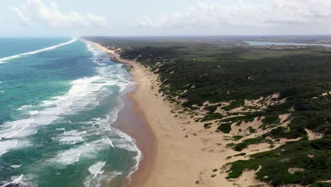 High-Altitude-Forward-Flying-Shot-of-Chidenguele-Beach-in-Mozambique-with-Inhampavala-Lake-in-Background