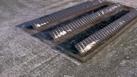 Aerial-drone-view-of-a-lightly-snow-covered-solar-panel-station-powering-a-farm