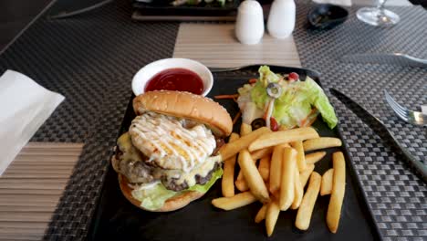A-delicious-burger-and-fries-served-on-a-beautiful-black-slate-plate