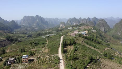 Wide-aerial-shot-of-a-farmland-surrounded-by-mountains-in-Yangshuo,-China
