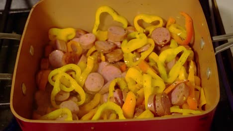Sausage-and-pepper-being-cooked-in-a-copper-pan