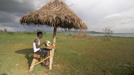 A-young-African-man-sits-down-at-a-beach-shelter-shack-on-the-shores-of-Lake-Victoria