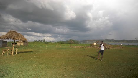 Slow-motion-shot-of-a-grass-field-by-the-shores-of-Lake-Victoria-and-a-young-African-doing-kick-ups
