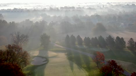 Rising-aerial-reveals-layers-of-illuminated-fog-during-October-sunrise-above-golf-course-in-Lancaster-PA