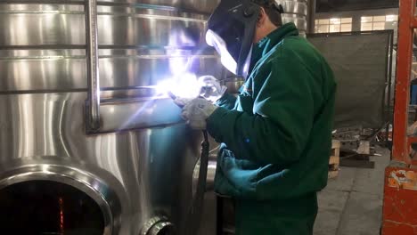 Worker-welding-stainless-steel-tank,-using-TIG,-MIG-welder,-close-up,-dolly,-slide,-movement