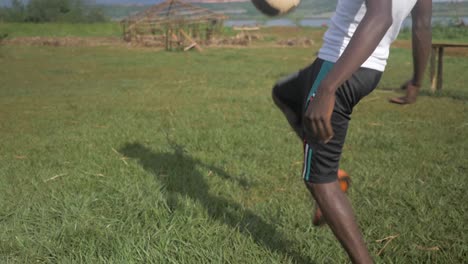 Slow-motion-close-up-shot-of-the-legs-of-a-young-African-mans-legs-as-he-does-kick-ups-with-a-football-on-a-grassy-field