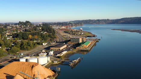 Sunny,-lateral-aerial-over-Coos-Bay,-Pacific-Northwest-lumber-mill-and-casino