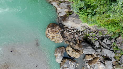 Aerial-bird's-eye-river-bank-with-big-rocks-alongside-a-huge-waterfall