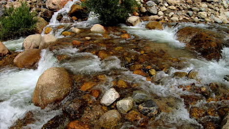 Slow-motion-video-of-fresh-water-running-downstream,-through-large-and-small-rocks